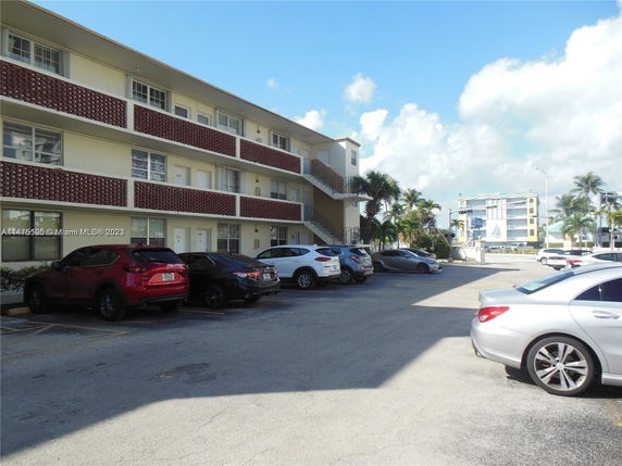 Outdoor parking area beside a multi-story residential building.