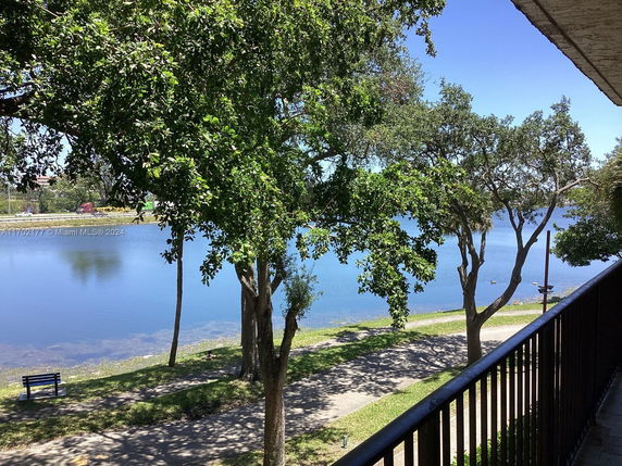 View of a lake with surrounding trees and a walkway, seen from a building.