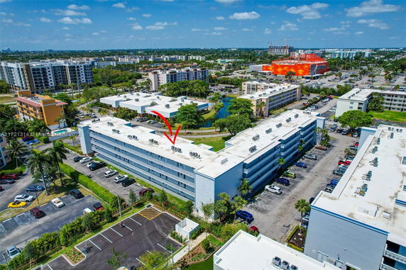 Aerial view of a multi-story building with white rooftops equipped with numerous air conditioning units.