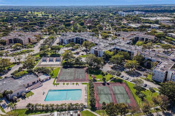 Aerial view of residential complex with tennis courts and swimming pool.
