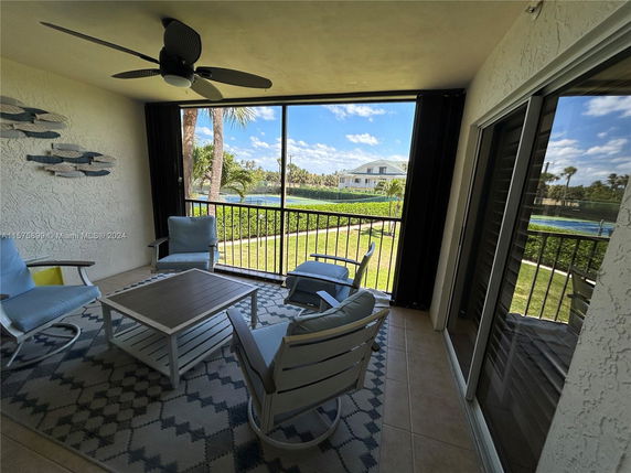 Balcony view with outdoor seating overlooking a lawn and distant house.