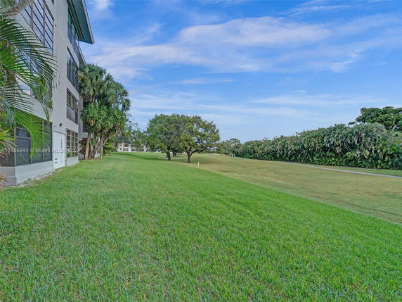 Side view of a multi-story building with surrounding lawn and trees.