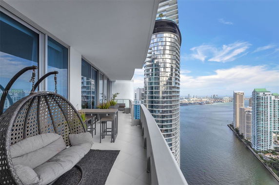 Balcony view from a high-rise building overlooking a river and surrounding skyscrapers.