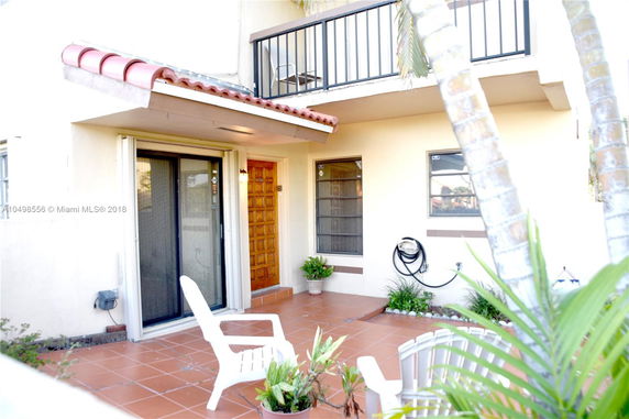 Front view of a house with a balcony and a patio area.