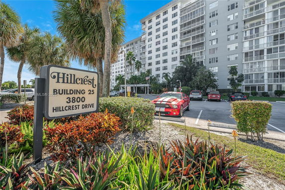 Front view of a multi-story residential building with a parking area in front.