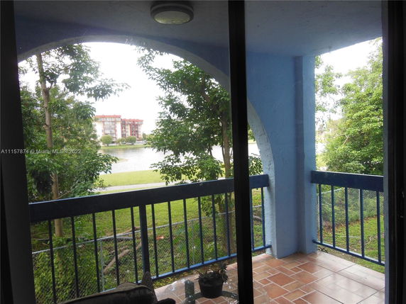 View from a balcony with blue railing overlooking a grassy area and a body of water.