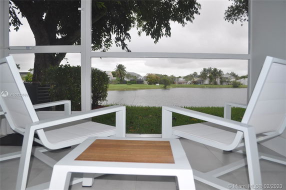 Outdoor seating area overlooking a lake and residential houses in the background.