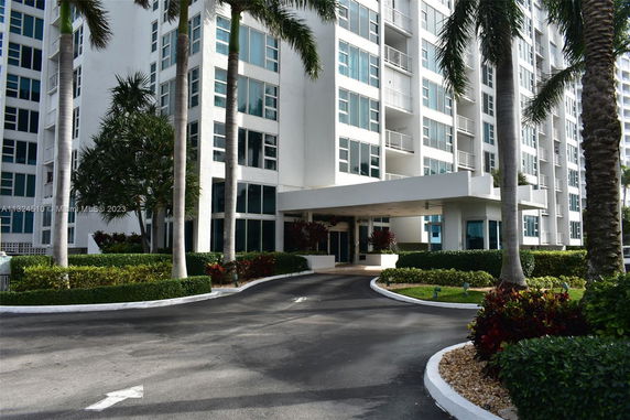 Front view of a multi-story building with a driveway and landscaped entrance.