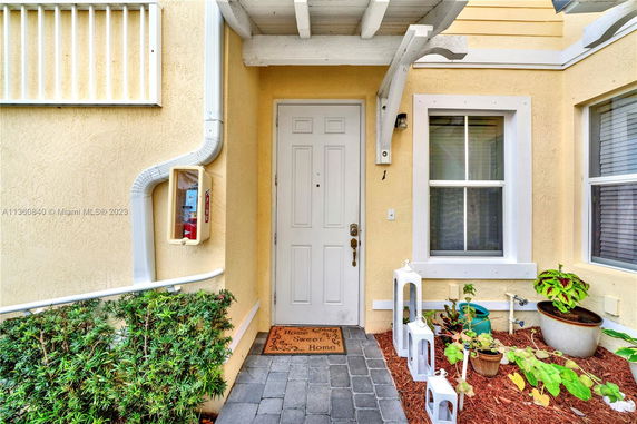 Front view of a house entrance with a covered porch and a welcome mat.