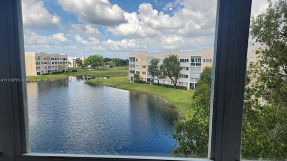 View of multiple-story apartment buildings by a lake, seen from a window.