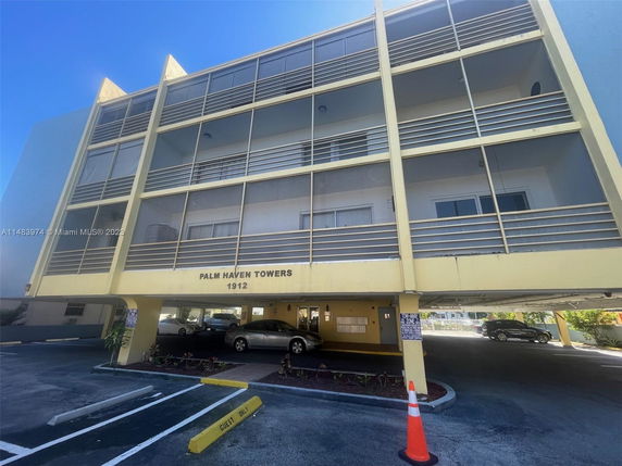 Front view of a multi-story building with parking area below.