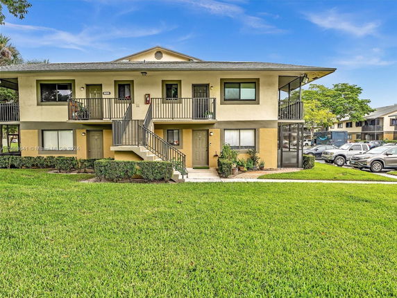 Front view of a two-story residential building with outdoor stairs and parking area.