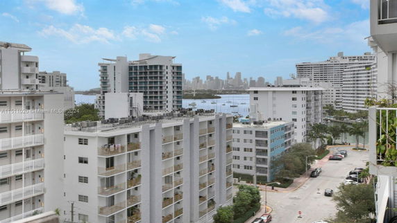 View of cityscape with multiple apartment buildings and distant skyline near water.
