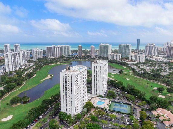 Panoramic view of a cityscape with tall residential buildings, golf course, and water features.