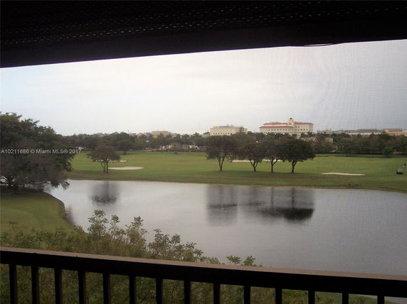 Panoramic view of a golf course with water and trees.