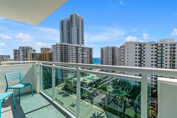 View from a balcony overlooking residential buildings and the ocean in the background.