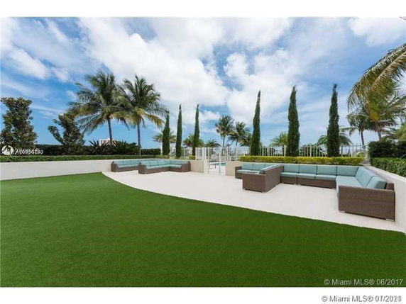 Outdoor seating area with greenery and palm trees.