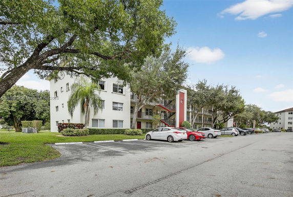 Front view of a multi-story apartment building with a parking area.