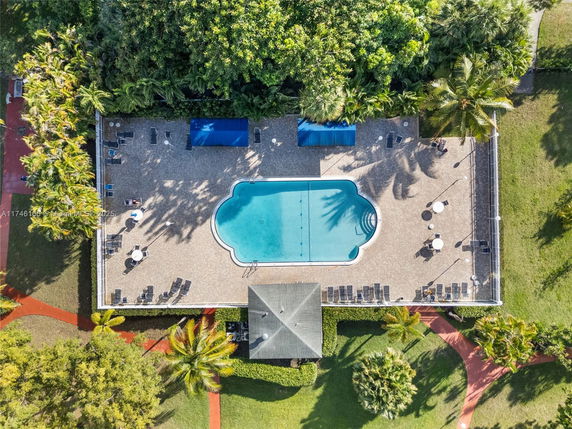 Top view of a swimming pool with surrounding deck area and vegetation.