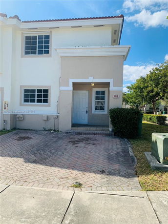 Front view of a two-story house with a small entrance and a paved driveway.