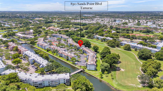Aerial view of a residential complex surrounded by greenery and water bodies.