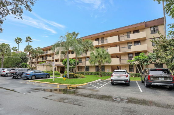 Front view of a multi-story residential building with balconies and parking area.