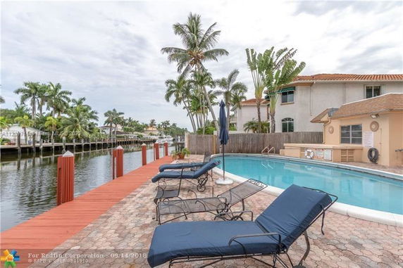 Outdoor swimming pool area with lounge chairs and palm trees.