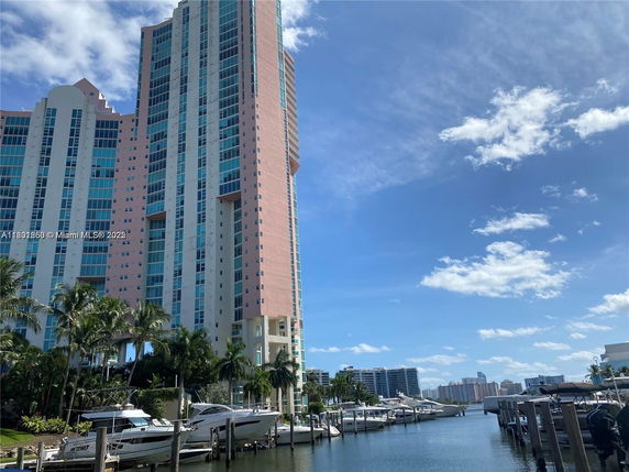 Front view of a high-rise residential building next to a marina with boats.