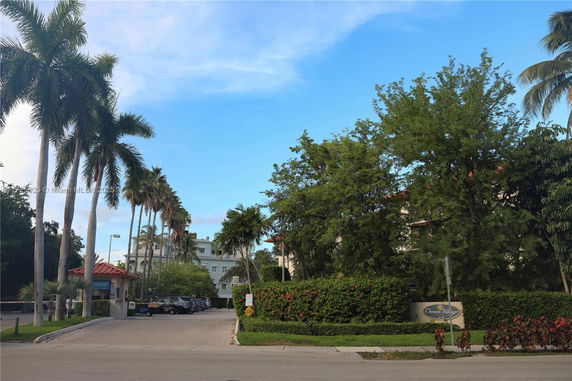 View of a building partially obscured by trees with a road leading to it.