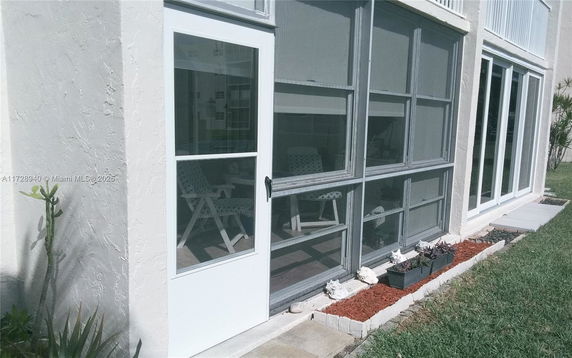 Partial view of a building with large windows and an outdoor seating area visible through the glass.