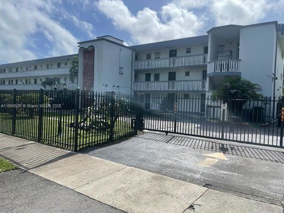 Front view of a three-story residential building with balconies and a gated entrance.