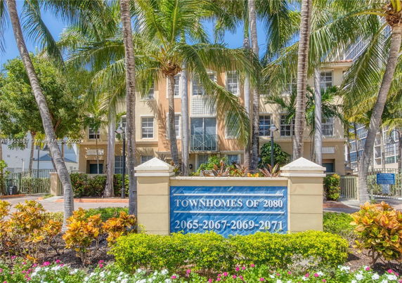 Front view of a multi-story townhome building with palm trees.