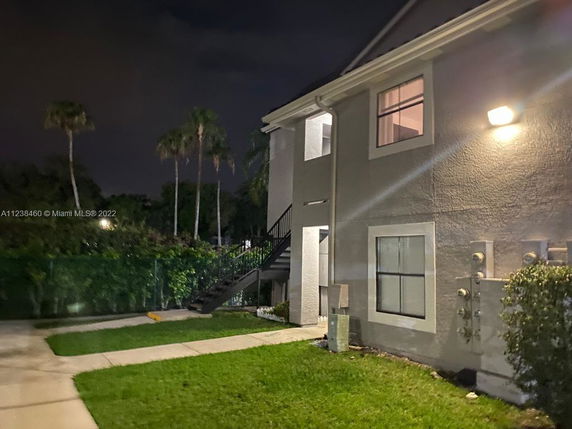 Side view of a two-story residential building with exterior staircase at night.