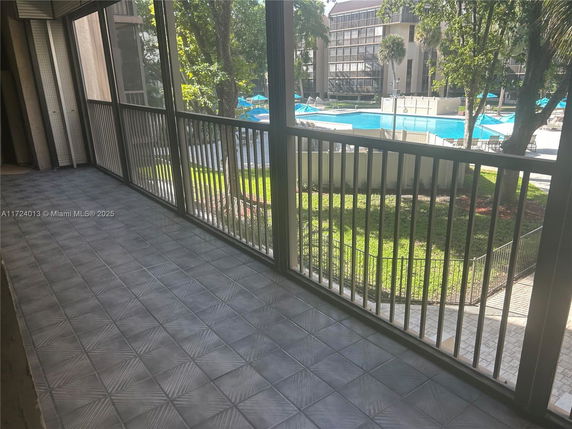 View from a balcony overlooking a swimming pool and surrounding area.