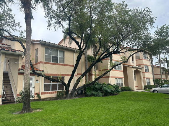 Front view of a multi-story residential building with external staircases and large windows.