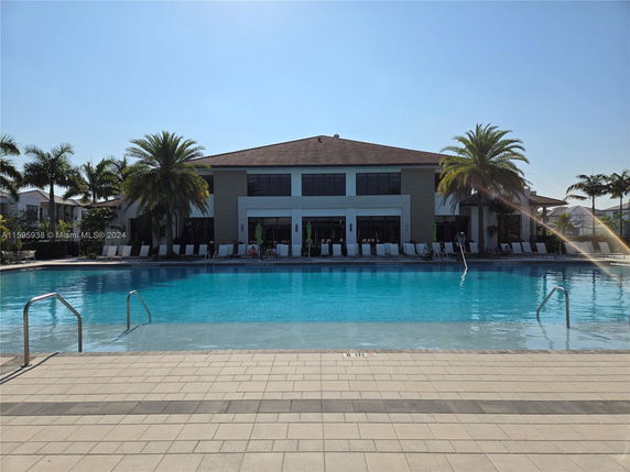 Front view of a modern two-story building with a large swimming pool in the foreground.