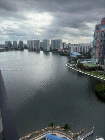 Panoramic view of a waterfront cityscape with tall buildings and an overcast sky.