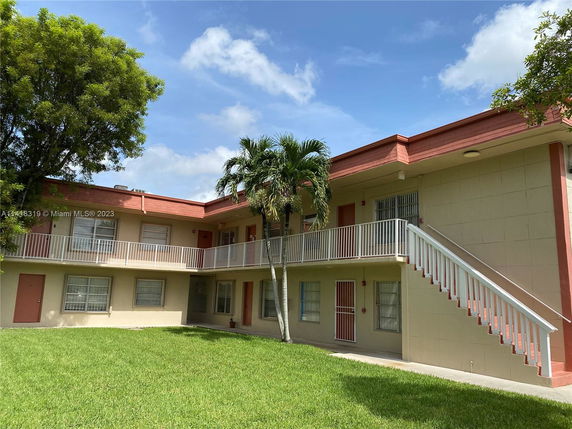 Front view of a two-story building with exterior staircases and railings.