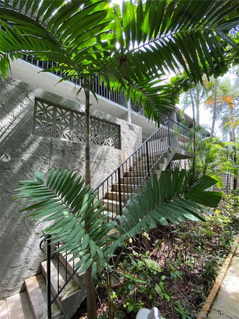 Front view of an outdoor staircase with leafy plants surrounding the building.