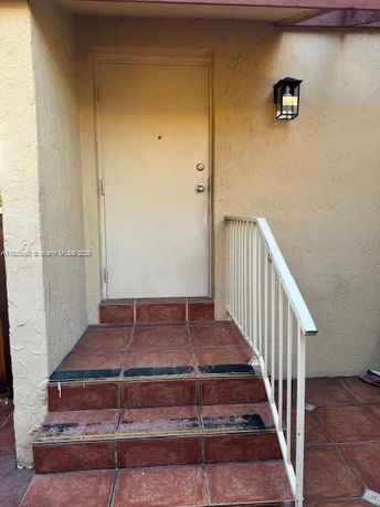 Front view of a residential entrance with steps and a railing.