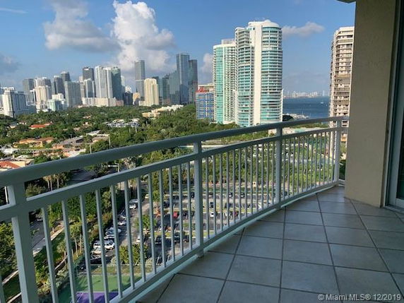 Balcony view of city skyline and surrounding areas with high-rise buildings.