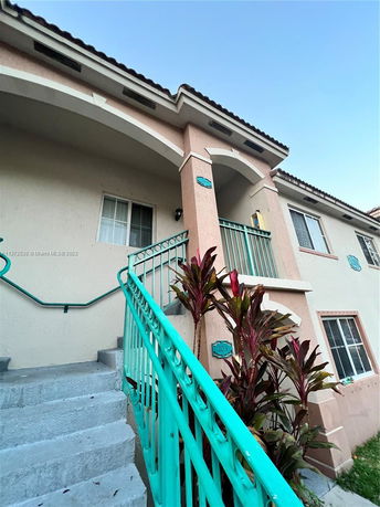 Front view of a multi-story building with stairs and archway.