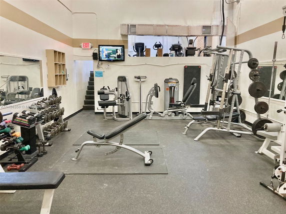 Indoor gym area with various exercise equipment and weights.