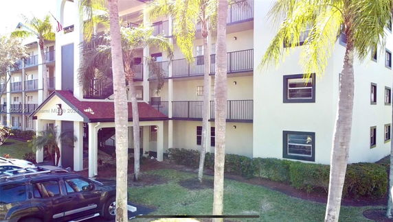 Front view of a multi-story residential building with balconies and a covered entrance.