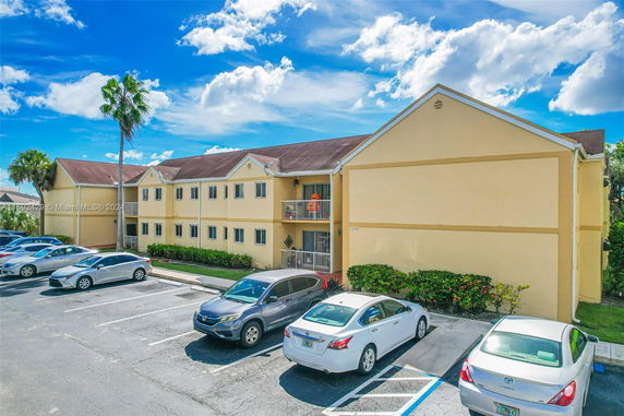 Front view of a two-story building with parked cars in front.