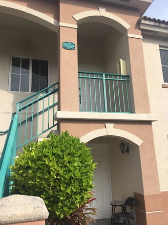 Front view of a two-story residential building with an arched entryway and a staircase.