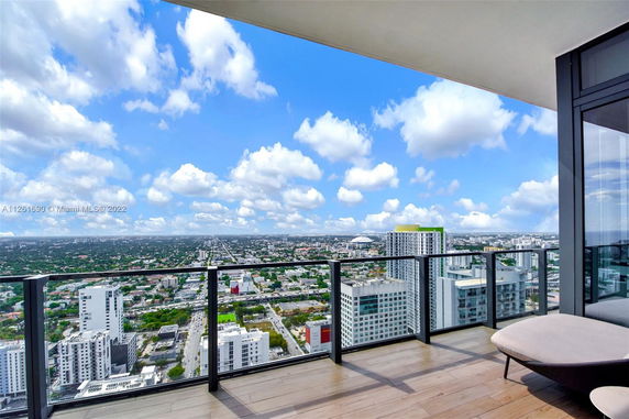 Panoramic view from a balcony overlooking a cityscape with tall buildings and a wide sky.