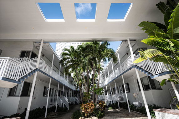 Courtyard view with two-story buildings and palm trees.
