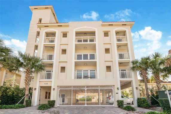 Front view of a multi-story residential building with balconies and a gated entrance.