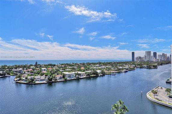 Wide angle view of waterway and distant buildings under a blue sky.
